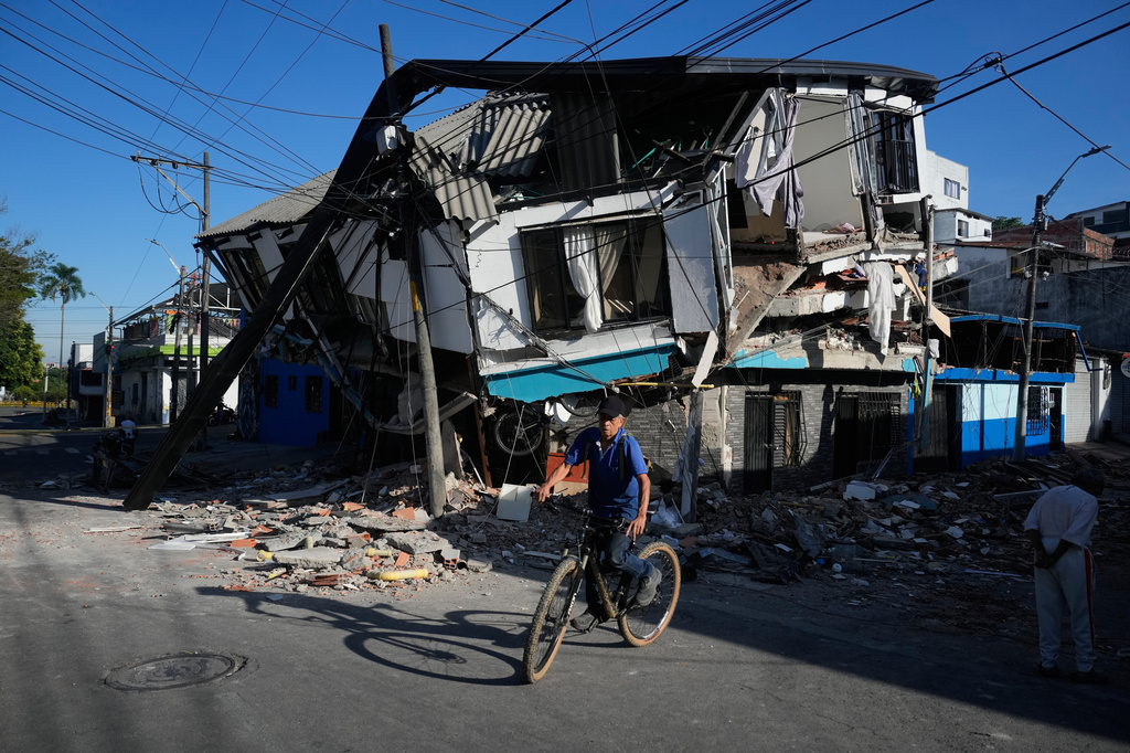 A neighbor rides past damaged homes a day after an earthquake struck Pereira, Colombia, Tuesday, Aug. 11, 2026. (AP Photo/Fernando Vergara)