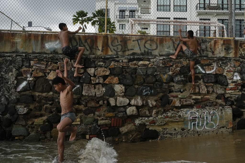 Youths climb a colonial-era wall to dive into the sea in the "Casco Viejo," the historic district of Panama City, a UNESCO World Heritage Site, Sunday, Aug. 10, 2025. (AP Photo/Matias Delacroix)