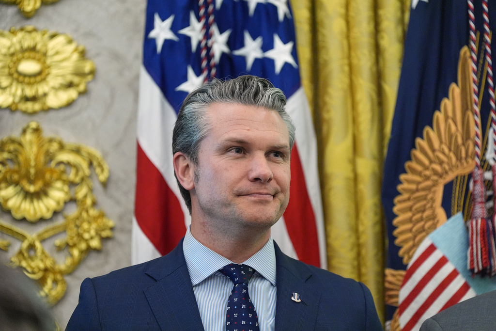 Defense Secretary Pete Hegseth listens as President Donald Trump speaks during the swearing in for Homeland Security Secretary Markwayne Mullin in the Oval Office of the White House, Tuesday, March 24, 2026, in Washington. (AP Photo/Alex Brandon)