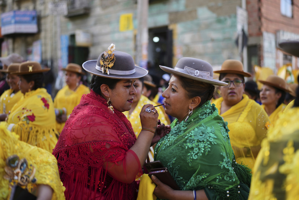 An Aymara woman applies lipstick on a fellow "cholita" during a campaign rally for presidential candidate Samuel Doria Medina, ahead of the Bolivia's upcoming general election, in La Paz, Aug. 12, 2025. (AP Photo/Natacha Pisarenko)