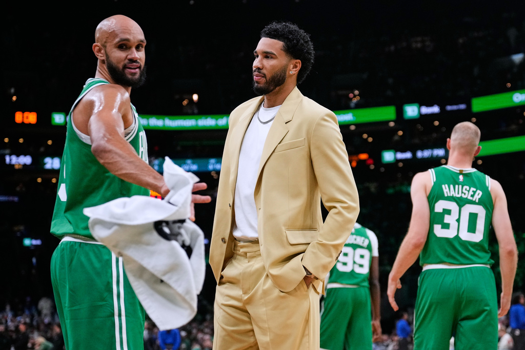 Boston Celtics forward Jayson Tatum, center, talks with guard Derrick White, left, during a time out in the first half of an NBA basketball game, Wednesday, Oct. 22, 2025, in Boston. (AP Photo/Charles Krupa)