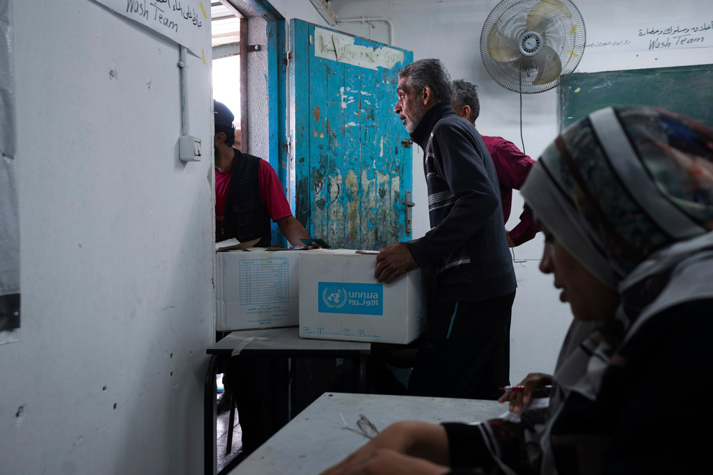 FILE - Palestinians receive aid distributed by UNRWA, the U.N. agency helping Palestinian refugees, in Nusairat refugee camp, Gaza, Nov. 5, 2024. (AP Photo/Abdel Kareem Hana, File)