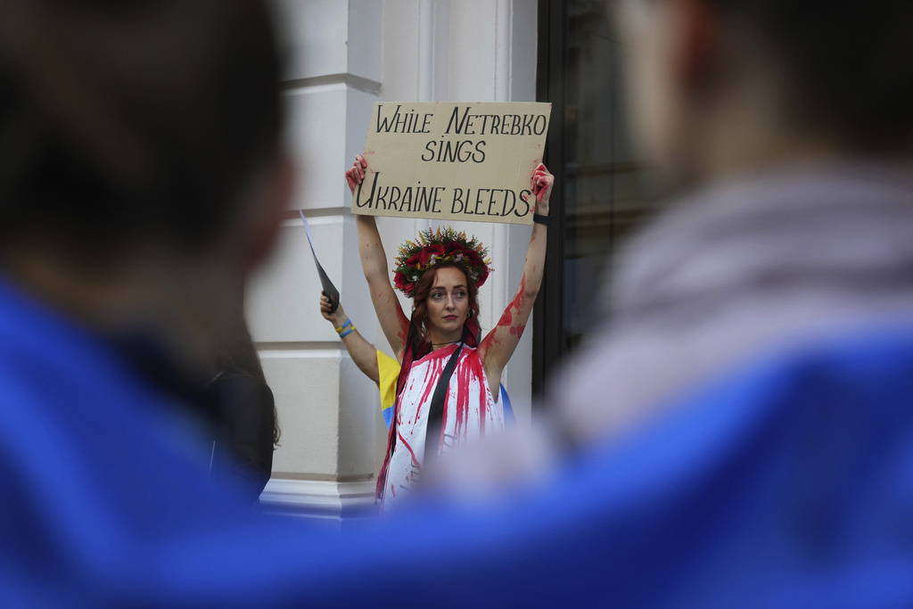 Pro-Ukraine protesters hold up placards and flags during a demonstration against the Royal Opera House in London, as the house had set an Russian opera singer to perform the lead in Puccini's Tosca, Thursday, Sept. 11, 2025. (AP Photo/Joanna Chan)
