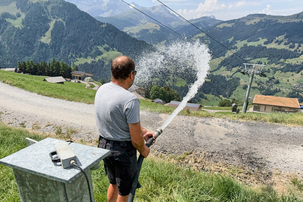 Juerg Klopfenstein, responsible for snowmaking operations at Adelboden-Lenk ski Resort, waters a road alongside ski slopes in Lenk valley near Adelboden, Switzerland, Monday, Aug. 3, 2026. (AP Photo/Hernan Munoz)