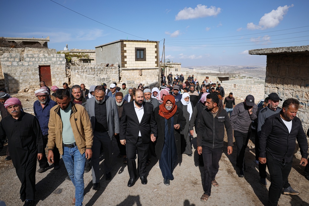 Residents follow the funeral procession of two women and a man killed when gunmen on motorcycles fired on a van near the Druze village of Kafr Maris in Syria's Idlib province, Wednesday, Oct. 22, 2025. (AP Photo/Omar Albam)