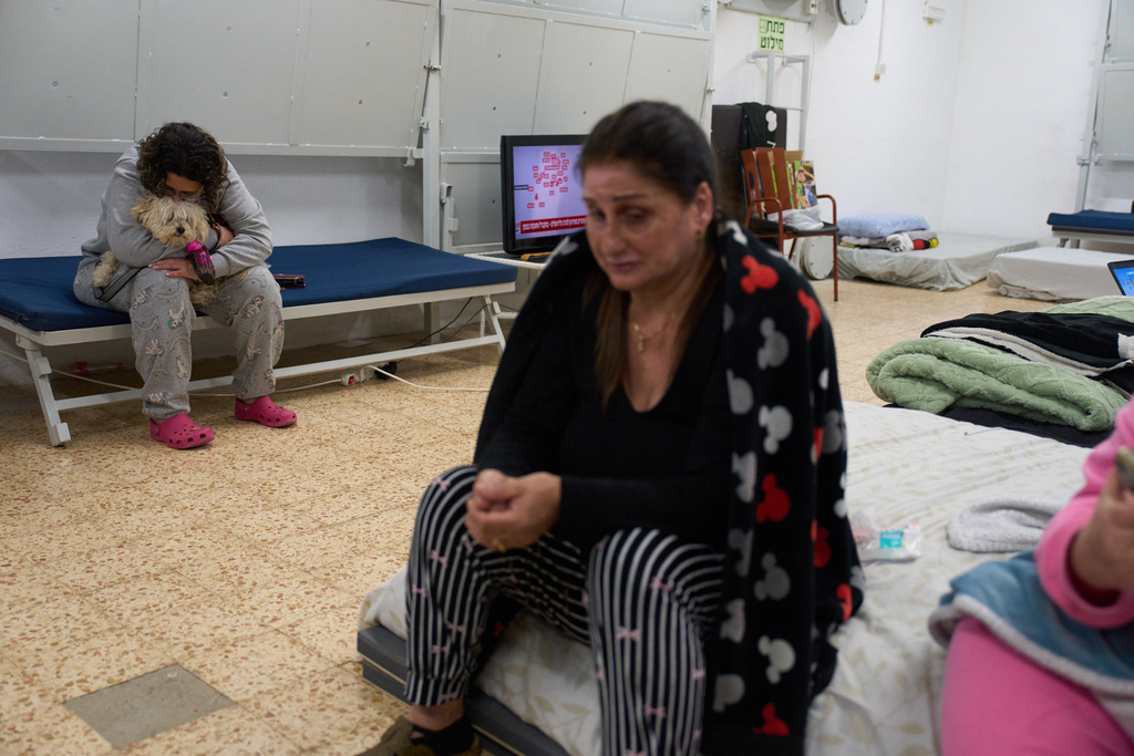 Nofar Eliash holds her dog as she takes shelter with others while air raid sirens warn of incoming Iranian and Hezbollah missile strikes in Kiryat Shmona, northern Israel, Monday, March 16, 2026. (AP Photo/Ariel Schalit)