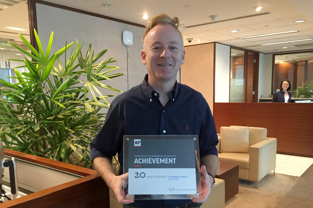 Christopher Bodeen holds up a certificate to celebrate his 20th year with The Associated Press at the office in Beijing, on July 21, 2016. (AP Photo/Ng Han Guan)