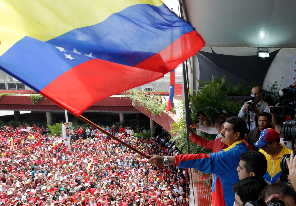 FILE - Venezuela's acting President Nicolas Maduro waves a national flag over supporters after registering his candidacy for president to replace late President Hugo Chavez at the national electoral council in Caracas, Venezuela, March 11, 2013. (AP Photo/Ariana Cubillos, File)