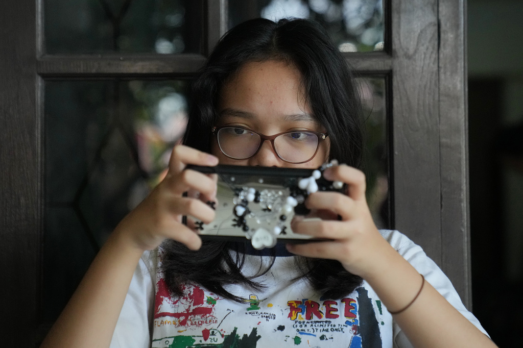 Maura Munthe plays Roblox on her mobile phone at her house in Jakarta, Indonesia, March 14, 2026. (AP Photo/Dita Alangkara)