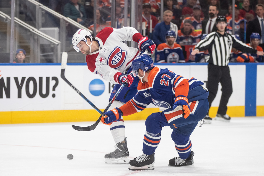 Montreal Canadiens' Josh Anderson (17) and Edmonton Oilers' Brett Kulak (27) battle for the puck during first period NHL action, in Edmonton on Thursday, Oct. 23, 2025. (Jason Franson/The Canadian Press via AP)