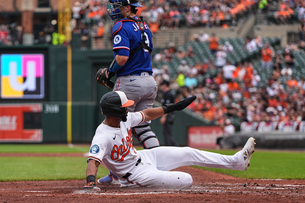 Baltimore Orioles' Leody Taveras scores past Texas Rangers catcher Danny Jansen on an RBI double hit by Taylor Ward during the second inning of a baseball game, Wednesday, April 1, 2026, in Baltimore. (AP Photo/Stephanie Scarbrough)