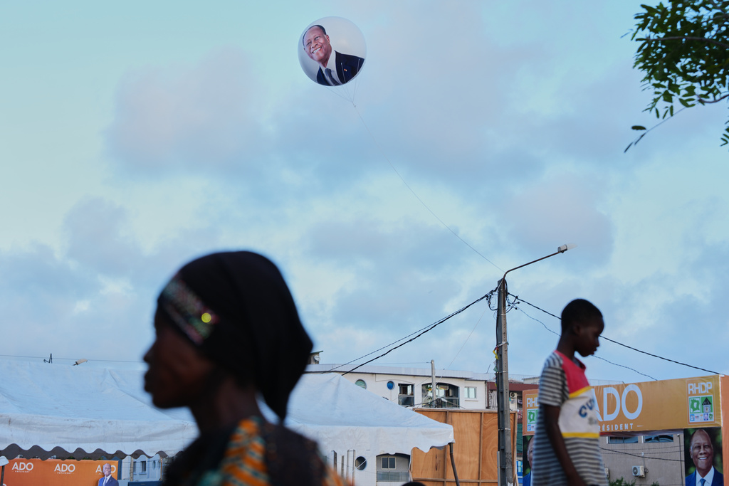 A balloon bearing the image of President Alassane Ouattara floats above supporters during a campaign rally in Koumassi, Abidjan, Ivory Coast, Wednesday, Oct. 22, 2025. (AP Photo/Misper Apawu)