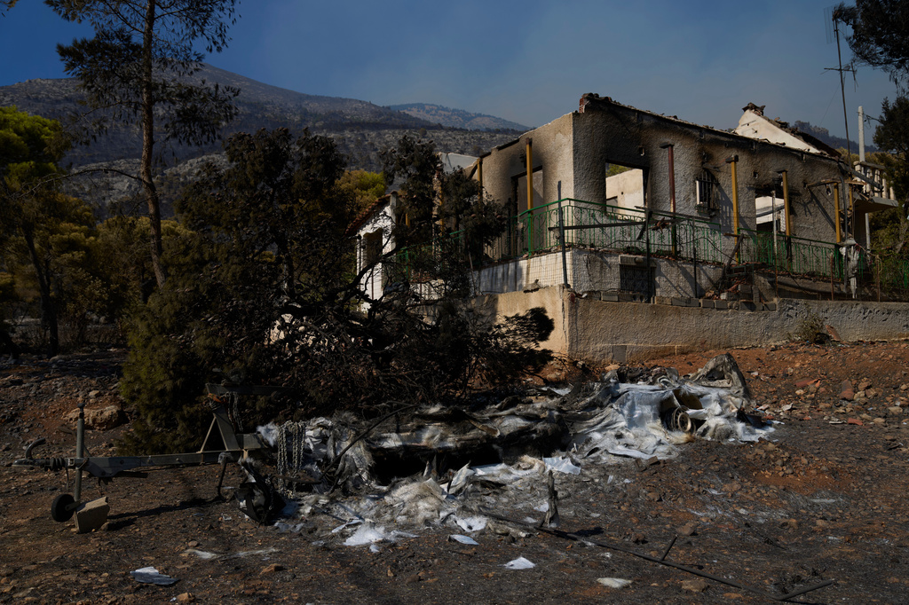 A house and a boat, destroyed by a wildfire, are seen in Porto Germeno, northwest of Athens, Greece, Monday, Aug. 3, 2026. (AP Photo/Petros Giannakouris)