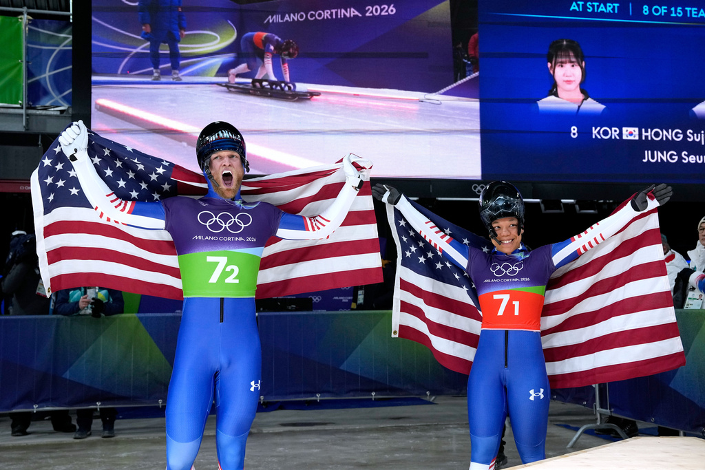 United States' Austin Florian, left, and United States' Mystique Ro celebrate at the finish during the skeleton mixed team competition at the 2026 Winter Olympics, in Cortina d'Ampezzo, Italy, Sunday, Feb. 15, 2026. (AP Photo/Alessandra Tarantino)