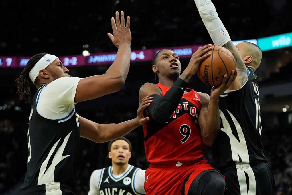 Toronto Raptors' RJ Barrett (9) drives to the basket between Milwaukee Bucks' Kyle Kuzma and Myles Turner during the first half of an NBA basketball game Sunday, Feb. 22, 2026, in Milwaukee. (AP Photo/Aaron Gash)