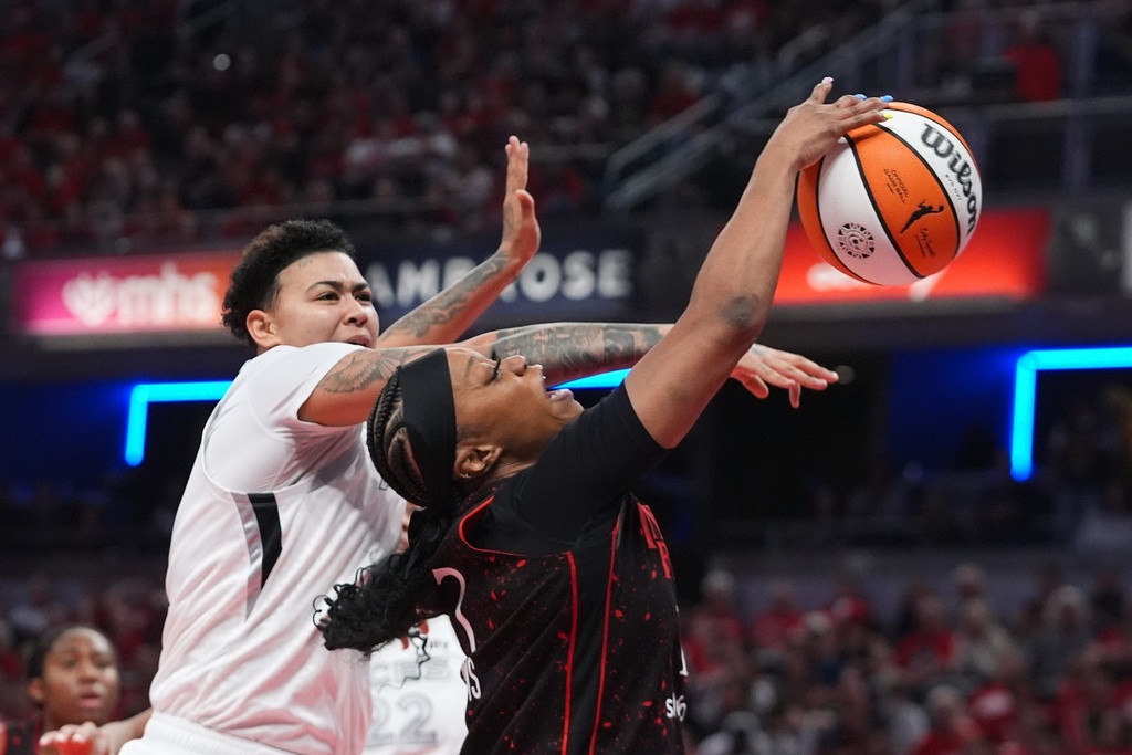 Indiana Fever's Odyssey Sims, right, has her shot blocked by Las Vegas Aces' Kierstan Bell during second half of Game 3 of a WNBA basketball playoff semifinals series, Friday, Sept. 26, 2025, in Indianapolis. (AP Photo/Darron Cummings)