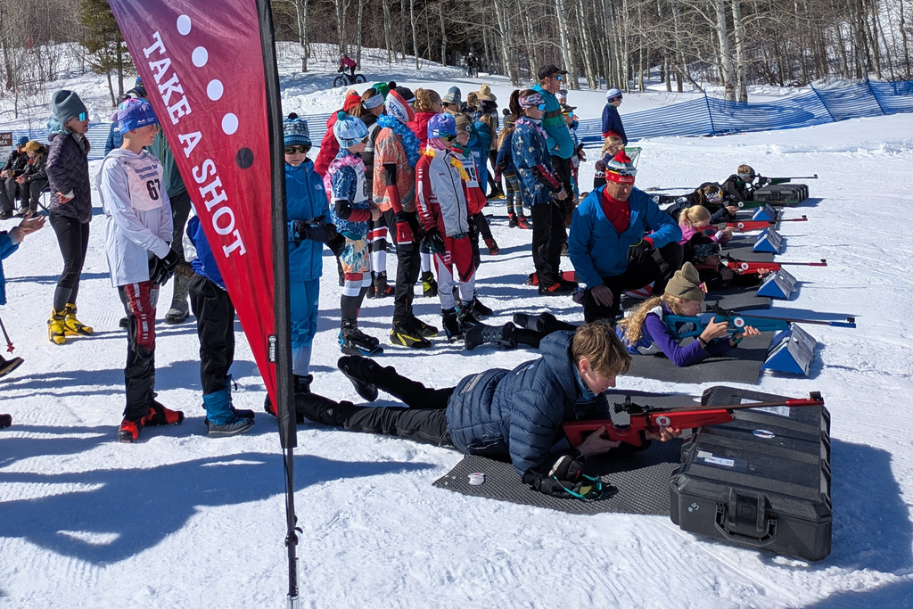 In this image provided by U.S. Biathlon young cross-country skiers attending the Intermountain Youth Ski Festival in Victor, Idaho on March 1, 2025, line up to take their turns shooting laser rifles provided by the U.S. Biathlon Association to help grow the sport. (John Farra/U.S. Biathlon via AP)
