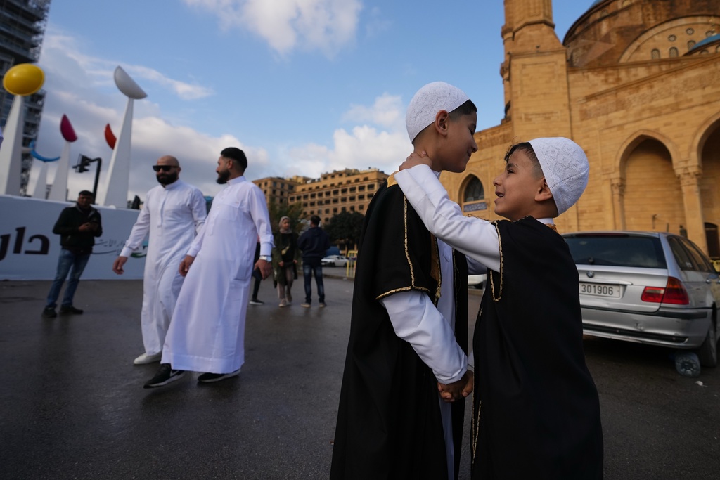 Two boys wearing new clothes for Eid greet each other outside the Mohammad Al-Amin Mosque during Eid al-Fitr celebrations in Beirut, Lebanon, Friday, March 20, 2026. (AP Photo/Hassan Ammar)