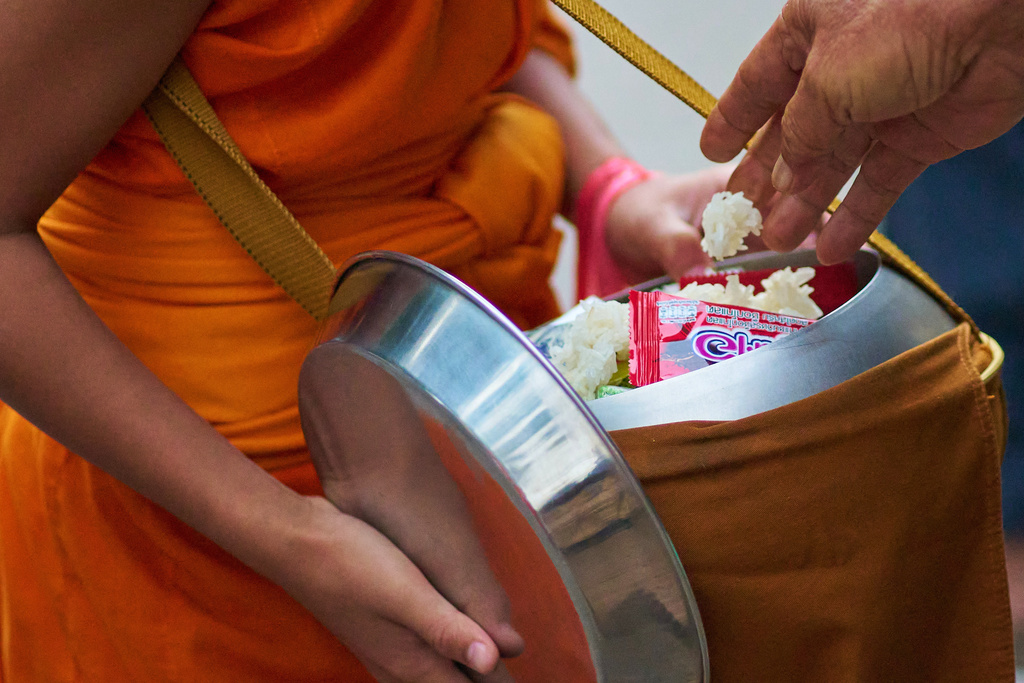 A novice Buddhist monk receives sticky rice as alms early morning in Luang Prabang, Laos, Friday, Nov. 7, 2025. (AP Photo/Eugene Hoshiko)