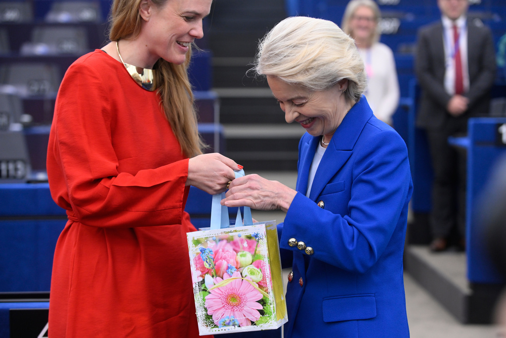 European Commission president Ursula von der Leyen, right, gets a gift for her birthday before delivering her statement on EU response to recent Russian violations of the EU Member States' airspace and critical infrastructure, Wednesday, Oct. 8, 2025 at the European Parliament in Strasbourg, eastern France. (AP Photo/Pascal Bastien)