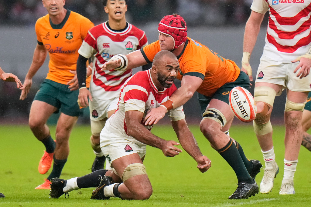 Japan's Michael Leitch, left, passes the ball as Australia's Harry Wilson attempts a tackle during a rugby test between the Wallabies and Japan in Tokyo, Saturday, Oct. 25, 2025. (AP Photo/Shuji Kajiyama)