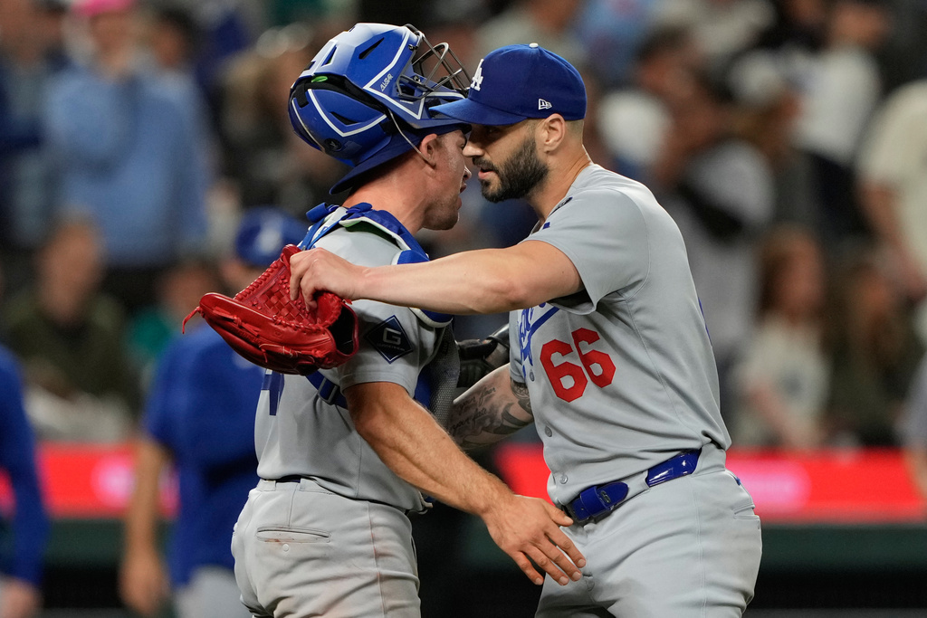 Los Angeles Dodgers relief pitcher Tanner Scott (66) hugs catcher Ben Rortvedt after the team's win in a baseball game against the Seattle Mariners, Friday, Sept. 26, 2025, in Seattle. (AP Photo/Ryan Sun)