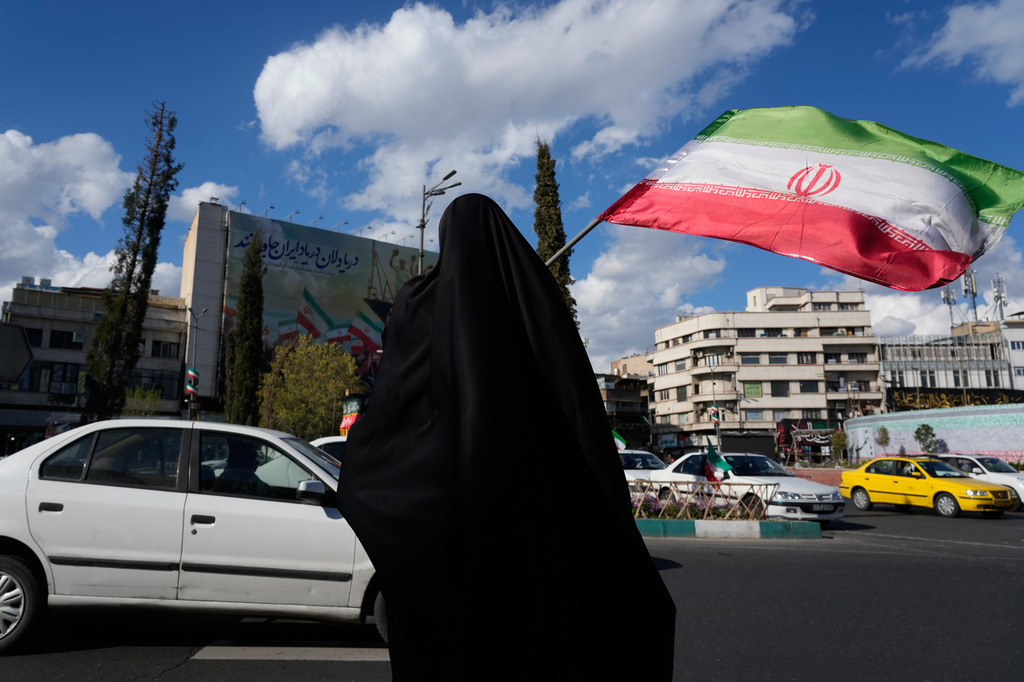 A woman waves an Iranian flag during a campaign in support of the government at the Enqelab-e-Eslami, or Islamic Revolution, square in downtown Tehran, Iran, Monday, March 30, 2026. (AP Photo/Vahid Salemi)