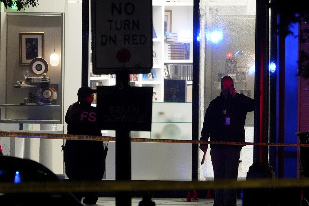 U.S. Secret Service Police examine and photograph evidence and shattered glass, seen right, at a crime scene near the White House, Saturday, May 23, 2026, in Washington. The U.S. Secret Service shot a person near the White House on Saturday, and a bystander also was shot, a law enforcement official said. (AP Photo/Alex Brandon)