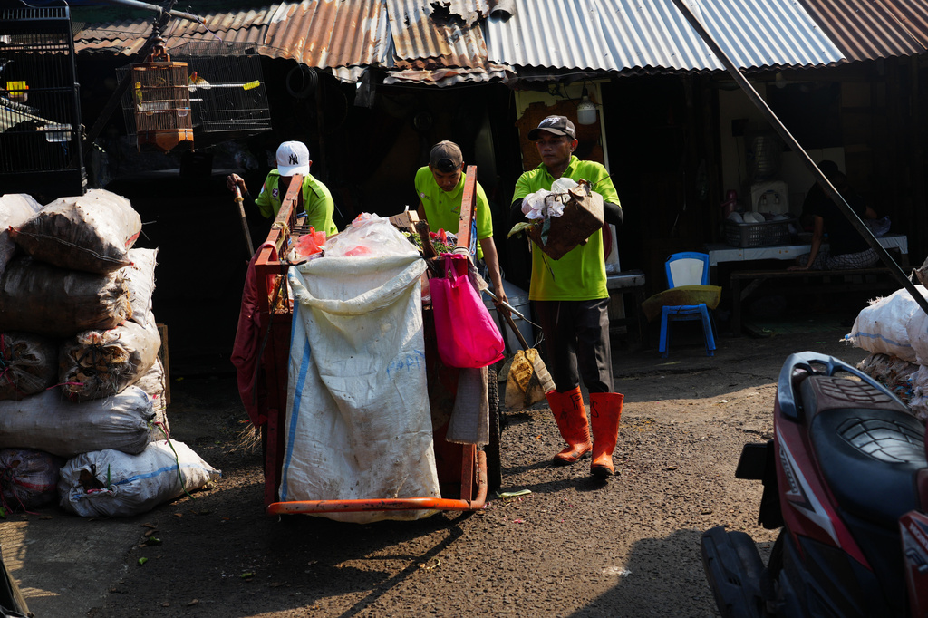Sanitation workers collect trash at a traditional market in Jakarta, Indonesia, Friday, July 17, 2026. (AP Photo/Tatan Syuflana)