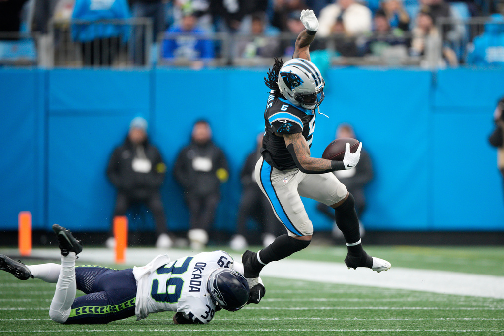Carolina Panthers running back Rico Dowdle is tackled by Seattle Seahawks safety Ty Okada during the first half of an NFL football game, Sunday, Dec. 28, 2025, in Charlotte, N.C. (AP Photo/Jacob Kupferman)