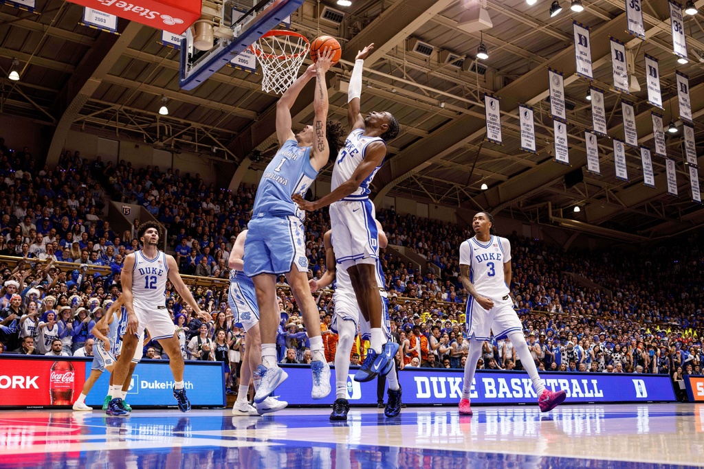 Duke's Dame Sarr (7) jumps to block a shot by North Carolina's Zayden High (1) during the first half of an NCAA college basketball game in Durham, N.C., Saturday, March 7, 2026. (AP Photo/Ben McKeown)