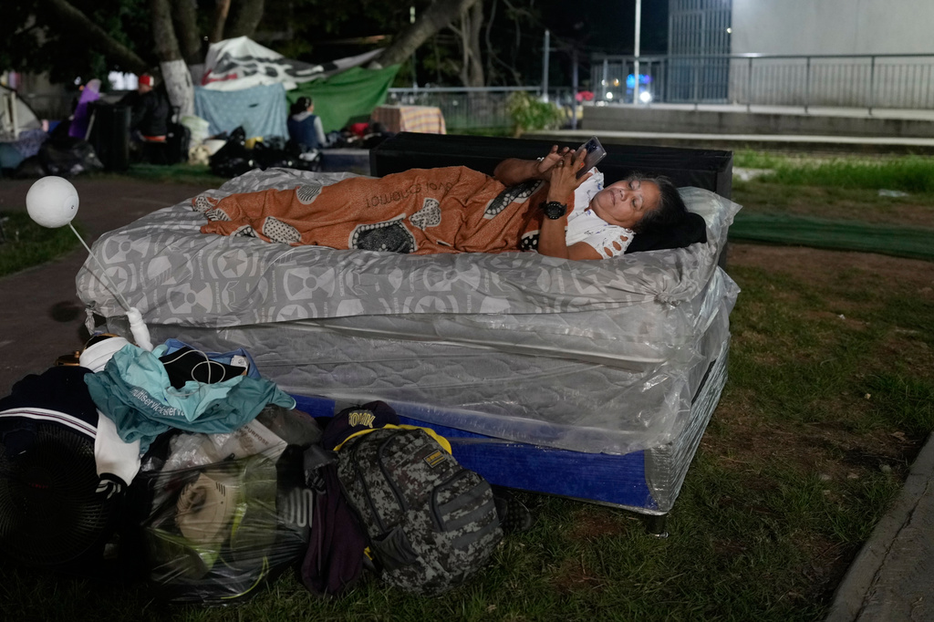 A woman rests in the street the night after earthquakes struck Caracas, Venezuela, Thursday, June 25, 2026.. (AP Photo/Ariana Cubillos)