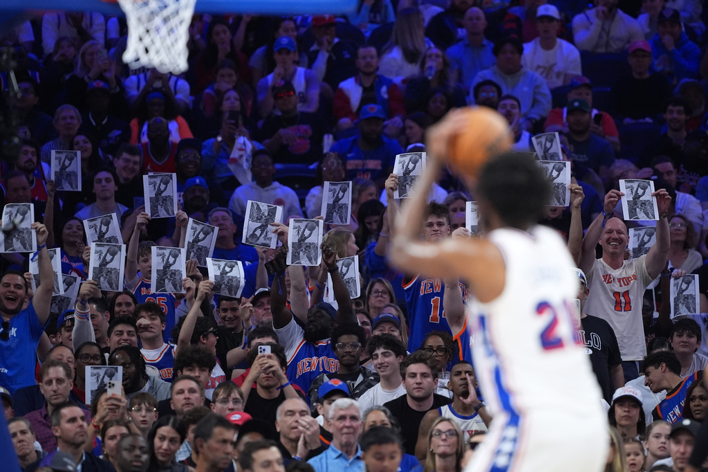 New York Knicks' fans hold up a photo as Philadelphia 76ers' Joel Embiid takes a free-throw shot during the first half of Game 4 against the New York Knicks in a second-round NBA basketball playoffs series Sunday, May 10, 2026, in Philadelphia. (AP Photo/Matt Slocum)