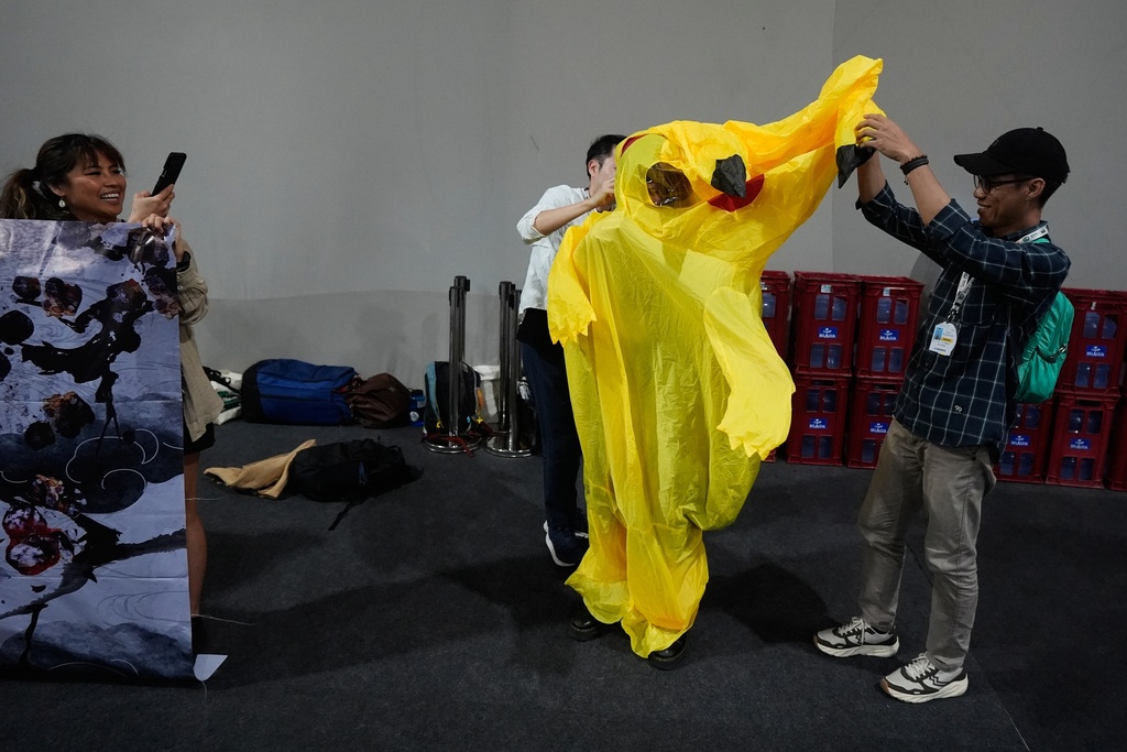 Activists, one trying to put on a Pikachu costume, protest Japan's financing of coal and natural gas projects during the COP30 U.N. Climate Summit, Friday, Nov. 14, 2025, in Belem, Brazil. (AP Photo/Fernando Llano)