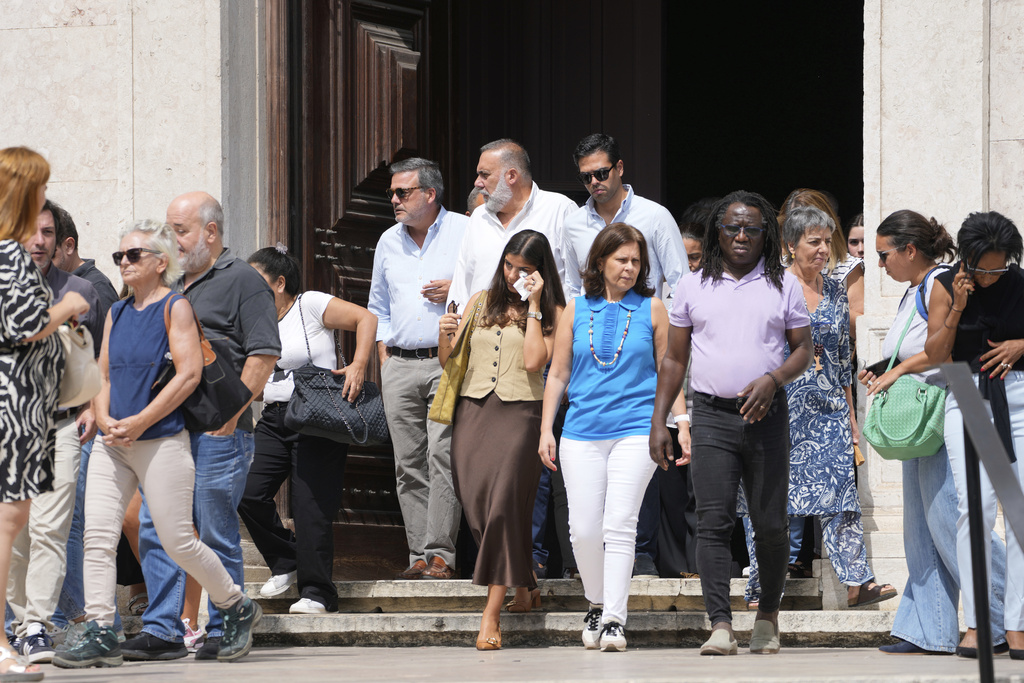 Relatives, friends and colleagues leave a church service for the four coworkers of the charitable organization Santa Casa da Misericordia who perished in the derailment and crash of the Gloria funicular, at the Church of Saint Roch in Lisbon, Friday, Sept. 5, 2025. (AP Photo/Armando Franca)