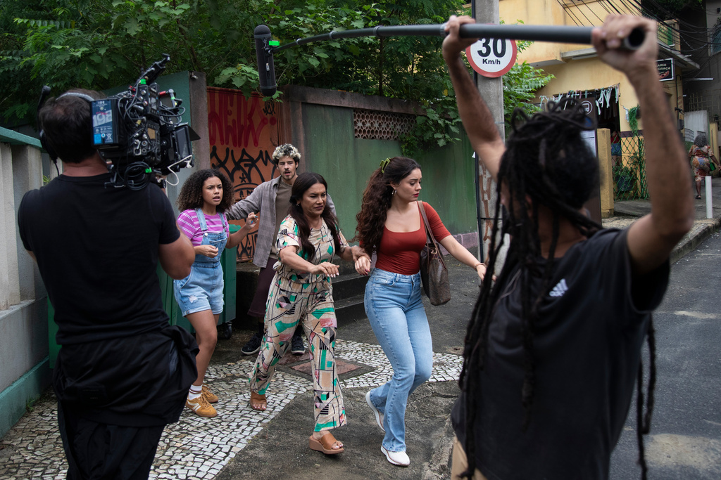 Actors Alana Cabral, behind left, Dira Paes, center, Sophie Charlotte, behind right, and Paulo Mendes, behind everyone, take part in the filming of the telenovela "Três Garças" at a TV Globo set in Rio de Janeiro, Thursday, March 12, 2026. (AP Photo/Bruna Prado)