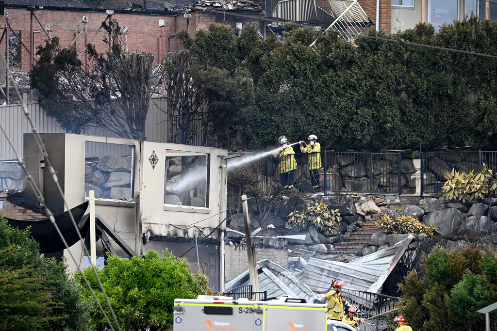 Firefighters ensure there are no flames left after a wildfire destroyed houses in Koolewong, Australia, Saturday, Dec. 6, 2025. (Dan Himbrechts/AAP Image via AP)
