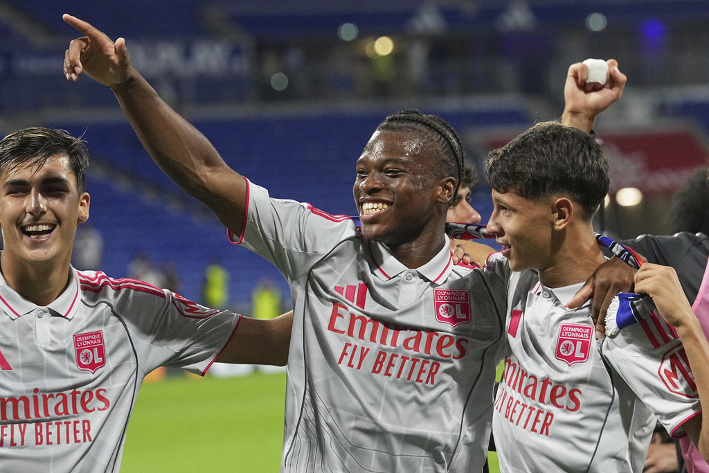 Lyon's Khalis Merah, right, and Lyon's Enzo Molebe, centre, celebrate after the French League One soccer match between Olympique Lyon and Angers at Groupama stadium in Decines, outside Lyon, France, Friday, Sept. 19, 2025. (AP Photo/Laurent Cipriani)