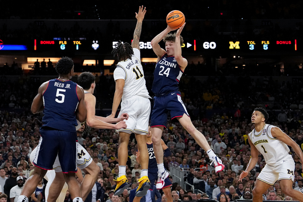 UConn guard Braylon Mullins (24) dishes off around Michigan guard Roddy Gayle Jr. (11) during the second half of the NCAA college basketball tournament national championship game at the Final Four, Monday, April 6, 2026, in Indianapolis. (AP Photo/Abbie Parr)