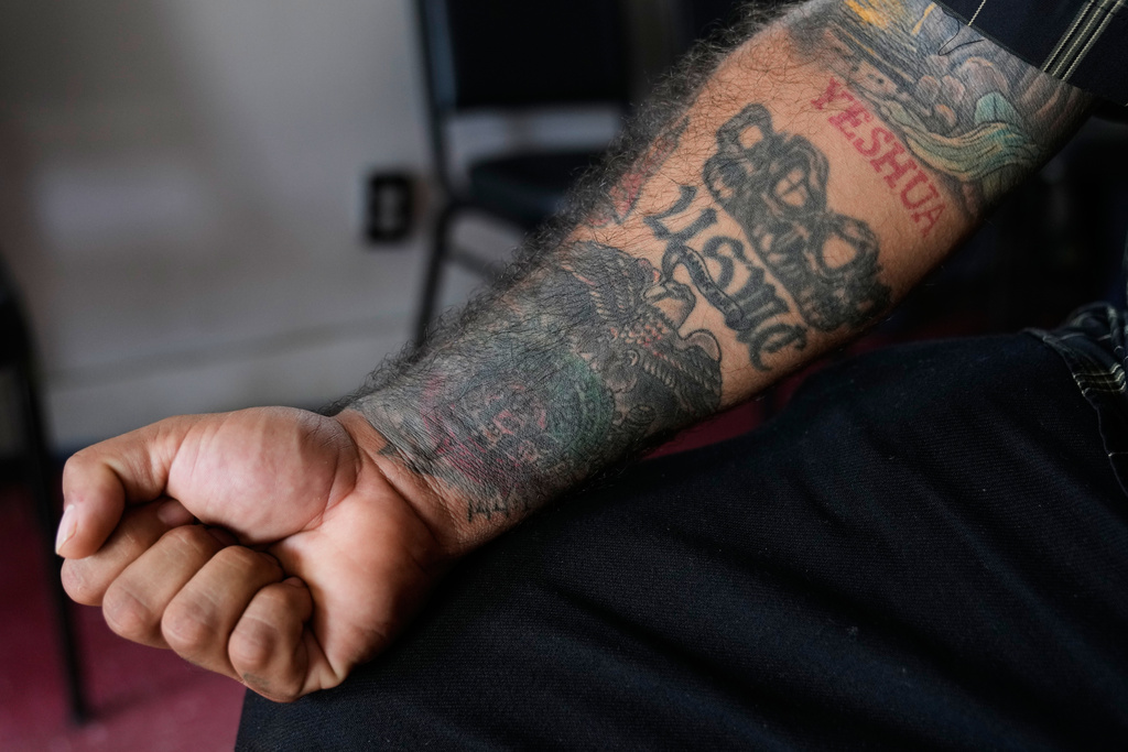 Julio Torres shows his USMC tattoo as he poses for a photo inside Serenity Corner, a church he founded nearly a decade ago, Monday, Sept. 22, 2025, in Terrell, Texas. (AP Photo/Tony Gutierrez)