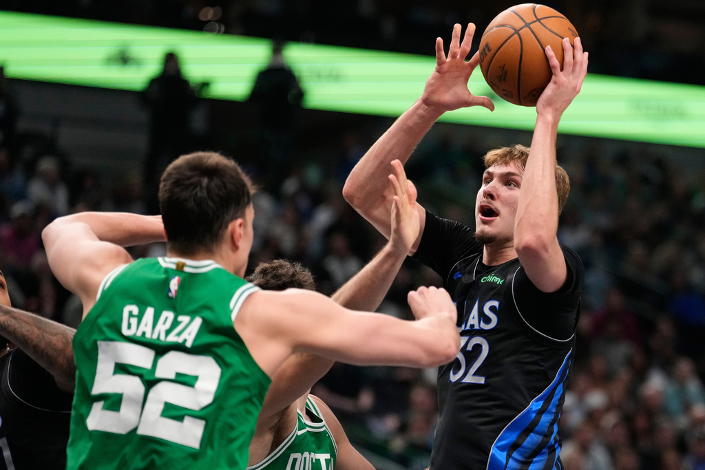 Dallas Mavericks' Cooper Flagg (32) takes a shot as Boston Celtics' Luka Garza (52) and Hugo Gonzalez, rear, defend in the first half of an NBA basketball game Tuesday, Feb. 3, 2026, in Dallas. (AP Photo/Tony Gutierrez)