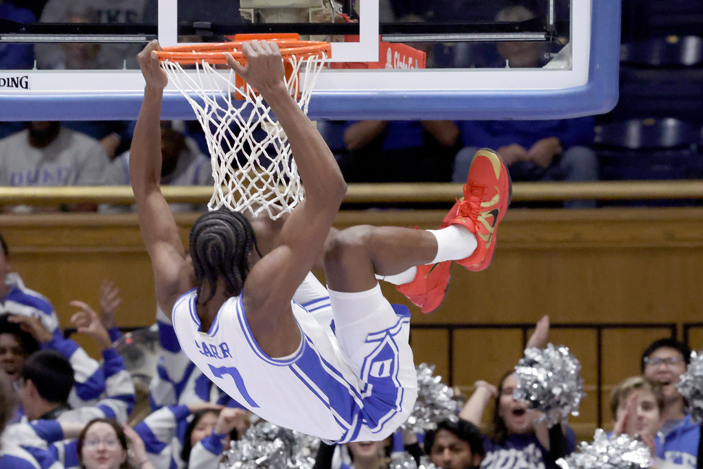 Duke guard Dame Sarr (7) hangs from the rim after dunking against Howard during the first half of an NCAA college basketball game Sunday, Nov. 23, 2025, in Durham, N.C. (AP Photo/Chris Seward)