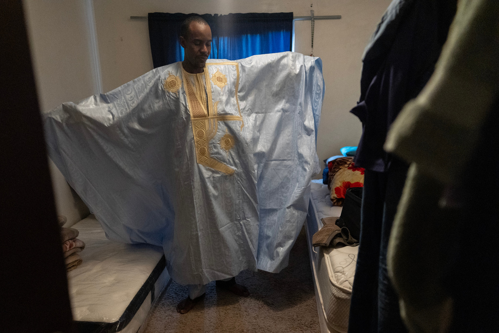 Samba Diallo displays his daraa, a loose-fitting traditional robe worn by men in Mauritania, as he stands in the bedroom of his shared apartment in Lockland, Ohio, Friday, July 17, 2026. (AP Photo/Carolyn Kaster)