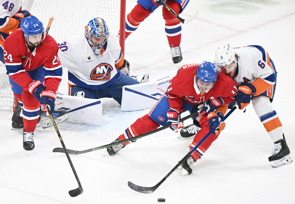New York Islanders goaltender Ilya Sorokin (30) looks on as Islanders' Ryan Pulock (6) defends against Montreal Canadiens' Brendan Gallagher (11) and Phillip Danault (24) during first period NHL hockey action in Montreal, Saturday, March 21, 2026. (Graham Hughes/The Canadian Press via AP)