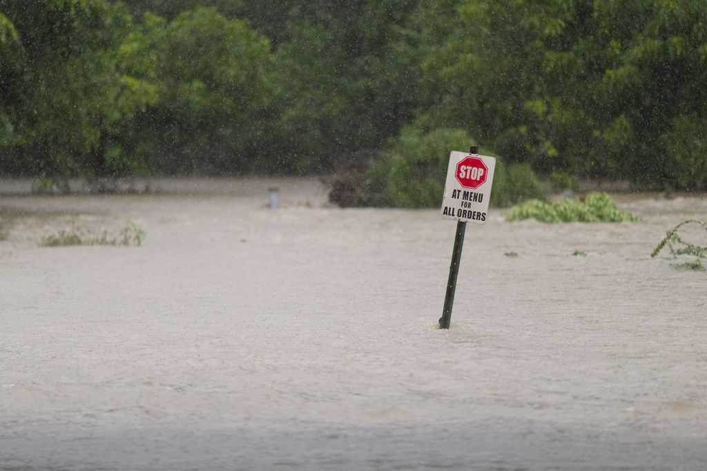 Flood water flows through a restaurant's parking lot on Wednesday, July 15, 2026, in Boerne, Texas. (AP Photo/Darren Abate)