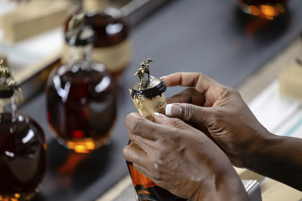 A worker places part of an ornate seal on a bottle of Blanton's bourbon in a bottling area at Buffalo Trace Distillery on Sept. 16, 2025, in Frankfort, Ky. (AP Photo/Jon Cherry)