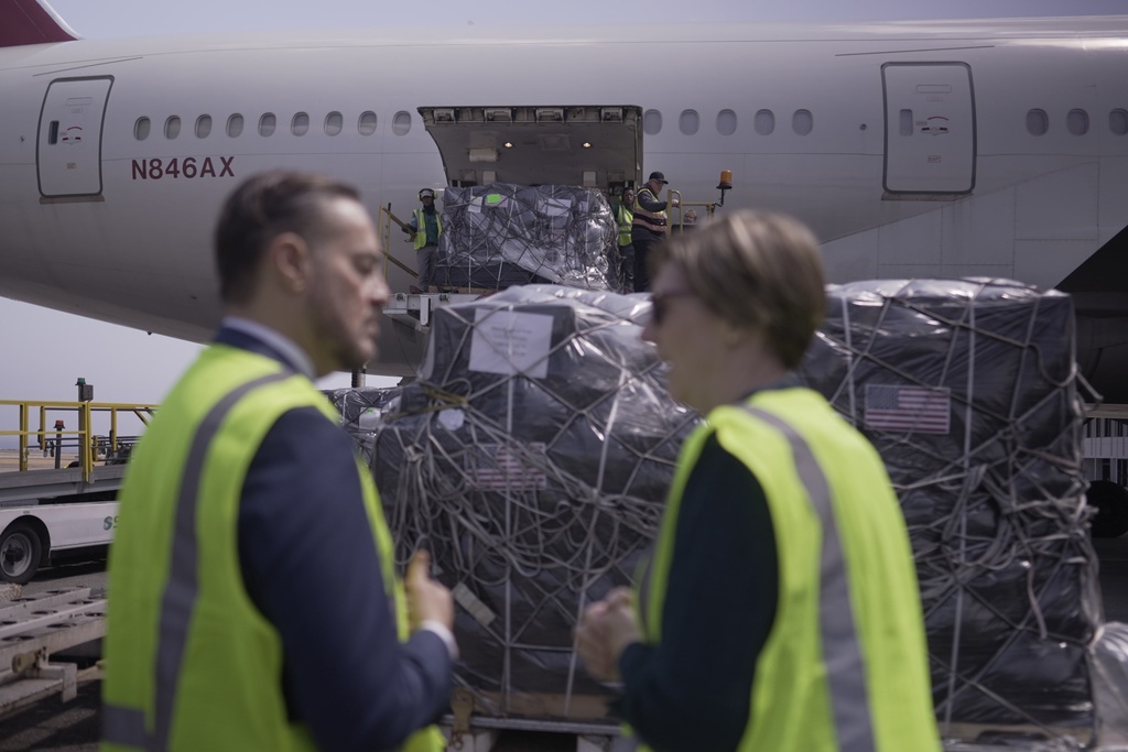 Pallets of medical supplies donated by the United States are unloaded as U.S. charge d'affaires Laura Dogu, right and Venezuelan diplomat Felix Plasencia stand by at the Simon Bolivar International Airport in Maiquetia, Venezuela, Friday, Feb. 13, 2026. (AP Photo/Juan Arraez)