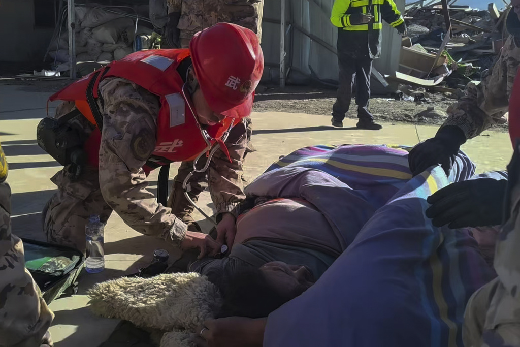 In this photo released by Xinhua News Agency, rescue workers check on an injured resident in the aftermath of an earthquake in Changsuo Township of Dingri in Xigaze, southwestern China's Tibet Autonomous Region on Tuesday, Jan. 7, 2025. (Liu Yousheng/Xinhua via AP)