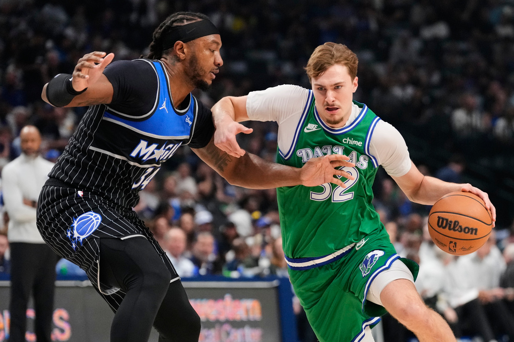 Dallas Mavericks forward Cooper Flagg (32) drives to the basket as Orlando Magic's Wendell Carter Jr. (34) defends in the first half of an NBA basketball game Friday, April 3, 2026, in Dallas. (AP Photo/Tony Gutierrez)