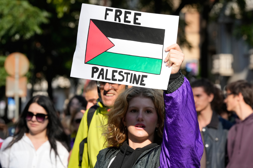 A pro-Palestinian demonstrator holds a banner as she gathers at a national general strike called by different unions to protest against the situation in Gaza two days after Israeli forces intercepted a Gaza-bound aid flotilla in the Mediterranean Sea, in Milan, Italy, Friday, Oct. 3, 2025. (AP Photo/Luca Bruno)